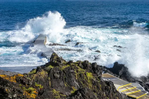 Cinco Ribeiras, Terceira, Azores, Portekiz 'in kıyı manzarası. Okyanus dalgaları engebeli volkanik kayalara çarpıyor ve Atlantik deniz manzarasının vahşi güzelliğini yakalıyor..