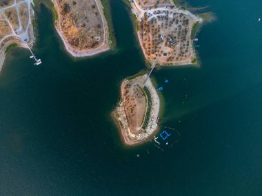 Portekiz, Alentejo 'daki Mouro Nehri plajının hava manzarası. Alqueva rezervuarının yanında, kumlu kıyılar, sakin sular ve rahatlama ve açık hava aktiviteleri için ideal manzara güzelliği sunuyor..