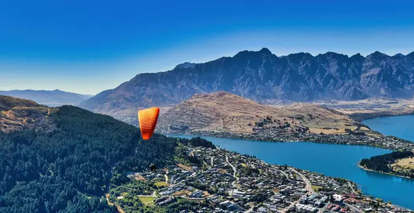 Queenstown Yeni Zelanda üzerinde paragliding, görkemli karlı dağlar arka plan, aşağıdaki köpüklü Wakatipu Gölü