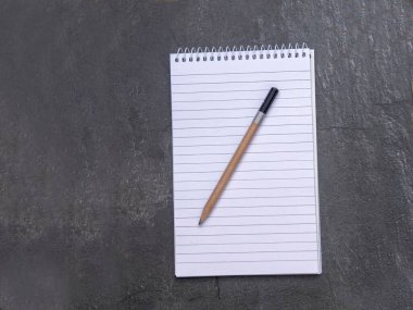 Astarlı kağıdın ve kalemin olduğu açık bir defterin üst görünümü, sarmal yayı olan okul defterleri, ofis notlarının düzlüğü.