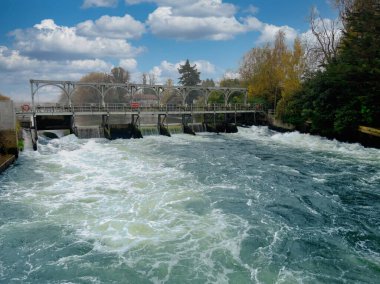 Su, Thames nehrinde balık merdiveni ile Beton bir Weir 'ın üzerinden akıyor.