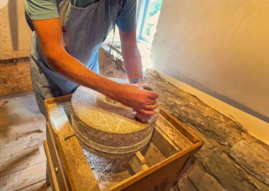 Değirmencinin elleri un yapmak için mekanik bir taş kullanarak un öğütüyor geleneksel un öğütücüsünü kullanarak eski taş öğütücüsünü kullanıyor..