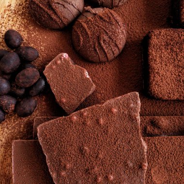 Çikolata. Çikolatalı kurabiye. Çikolatalı badem. Kakao tozu ve çikolatalı kek. Kapatın. Karanlık bir arka planda