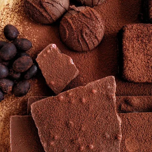 Çikolata. Çikolatalı kurabiye. Çikolatalı badem. Kakao tozu ve çikolatalı kek. Kapatın. Karanlık bir arka planda