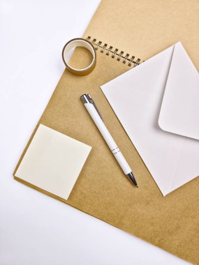 Zarf, kalem, yapışkan bant ve beyaz arkaplanda yarı saydam yapışkan bir not.