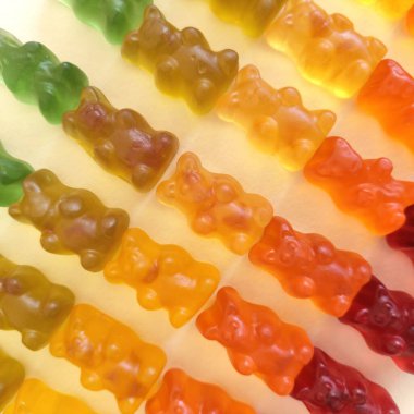 Gummy bears on a light background. Different colors: red, orange, yellow and green. Close up clipart