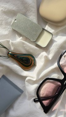 Yüz kremi, güneş kremi, pembe güneş gözlüğü, sağlam parfüm ve cam kolye de dahil olmak üzere yüz ve vücut bakımı gereksinimlerini içeren şık bir düzenleme.