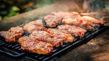 Izgaranın yakın plan çekimi ızgaralarda birden fazla biftek cızırtısı, etten yükselen duman.