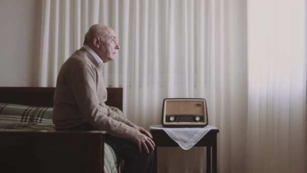 Ένας Ηλικιωμένος Λευκός Άντρας Κάθεται Ένα Κρεβάτι Κοιτάζοντας Έξω Από — Αρχείο Βίντεο