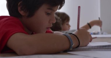 Yakışıklı çocuk ders çalışıyor, ödevini yapıyor. Evde masada oturan tatlı bir çocuk. Çocuklar için ev okulu. Kendin öğren. Akıllı okul çocuğu oturma odasında görevini yapıyor..