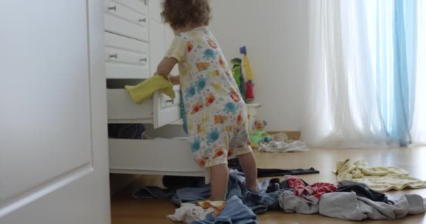 一岁的男婴把衣服从衣橱 凌乱的卧室 玩耍和在室内玩乐的地方扔了出来 视角也很低 — 图库视频影像