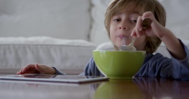 Üç yaşında bir çocuk kahvaltısını yaparken dijital tablet kullanıyor.
