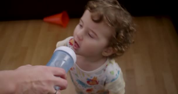 Chłopiec Kręconymi Włosami Patrzy Butelkę Oferowaną Przez Dorosłą Rękę Ojciec — Wideo stockowe