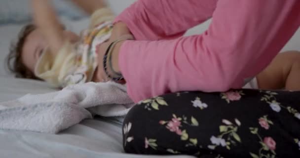 ピンクのシャツの女性は彼女の赤ちゃんの男の子におむつを変更する — ストック動画