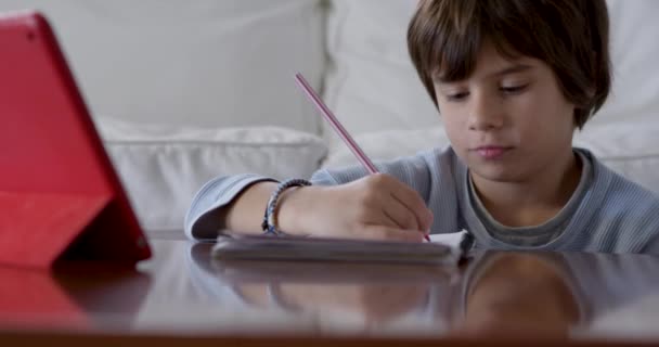 Χαριτωμένο Αγόρι Κάνει Την Εργασία Του Κάθεται Ένα Τραπέζι Χρησιμοποιώντας — Αρχείο Βίντεο
