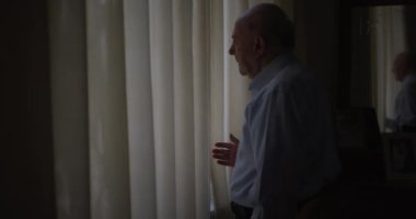 Son sınıf öğrencisi pencerenin kenarında dikiliyor, perdelerden bakıyor, düşüncelere dalmış..