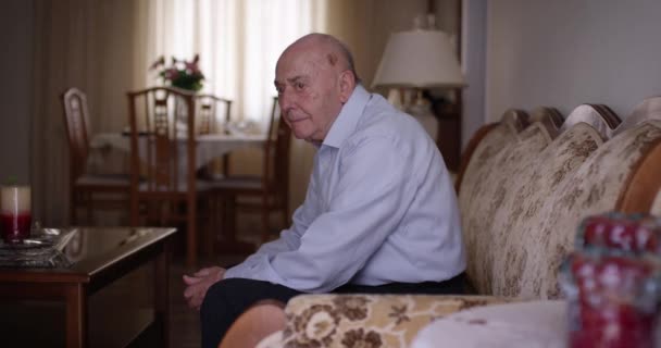 Пожилой Человек Сидящий Один Диване Хорошо Освещенной Гостиной Днем Выглядит — стоковое видео