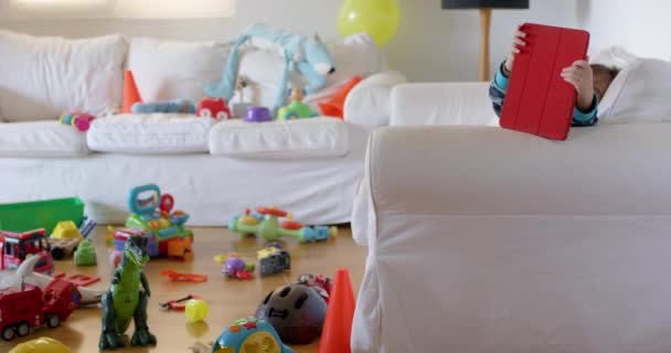 Dítě Sedí Pohovce Hraje Tabletem Obklopeným Roztroušenými Hračkami — Stock video