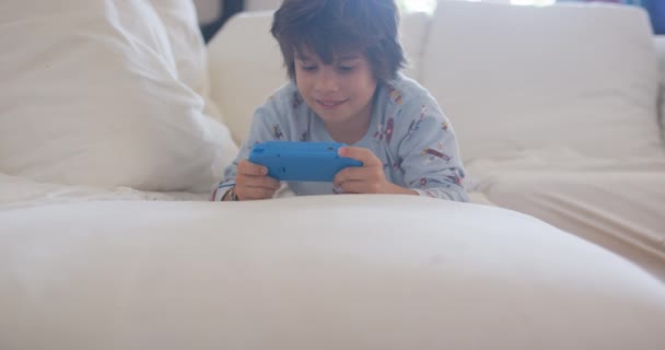 Bir Çocuk Beyaz Bir Kanepede Yatarken Bilgisayarı Üzerine Odaklanmış — Stok video