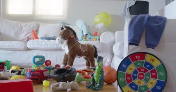 さまざまな子供のおもちゃの混乱が乱雑なリビングルームの床に広がり 子供のパーティーの後の遊び時間を示唆しています — ストック動画