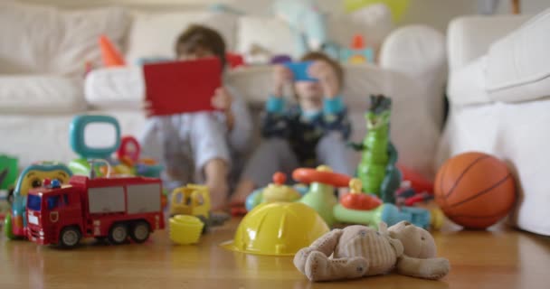 兄弟姐妹们正在玩电玩 包括铺在地板上的填充动物和玩具汽车 把注意力集中在前景上 — 图库视频影像