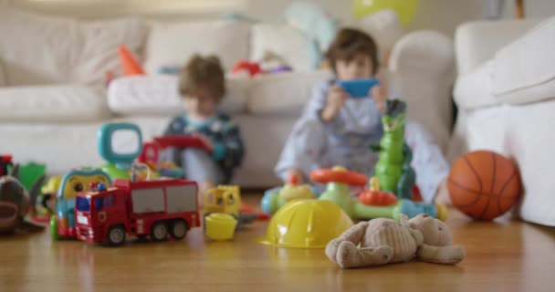 Geschwister Spielen Mit Elektronischen Konsolen Darunter Ein Stofftier Und Spielzeugautos — Stockvideo