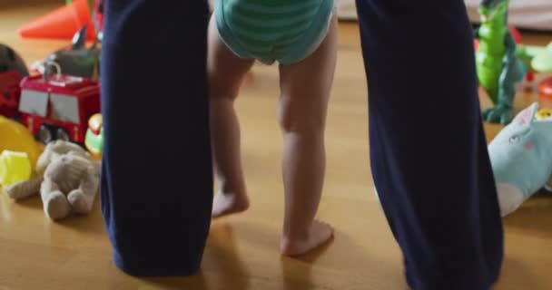 赤ちゃんが第一歩を踏み出す 母親は子供を抱きかかえて支え 家で歩くことを教えます 子供の人生の最初の年 高品質4K映像 — ストック動画
