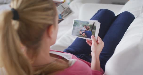 Jovem Mãe Deitada Sofá Sala Estar Assistindo Fotos Impressas Família — Vídeo de Stock