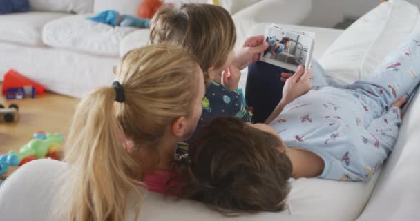Ung Mor Med Sine Børn Liggende Sofaen Stuen Ser Trykte – Stock-video