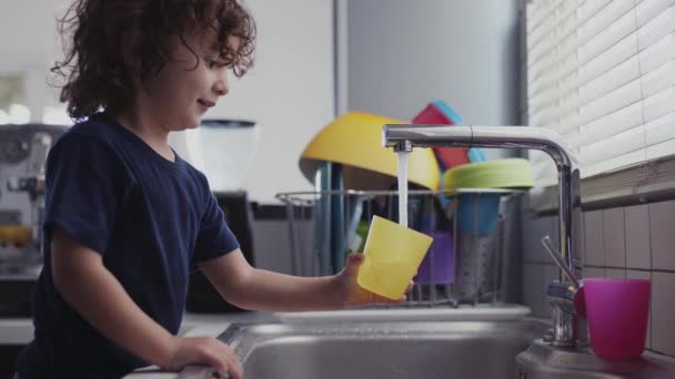 Маленька Дитина Весело Грає Водою Раковині Сучасній Кухні Наповнює Пластикову — стокове відео