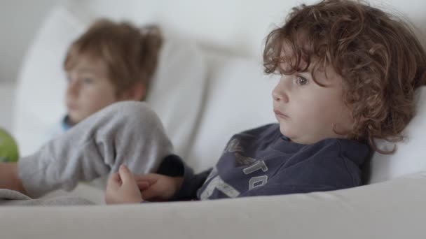 孩子们躺在沙发上 在一个现代化的客厅里 看电视 — 图库视频影像