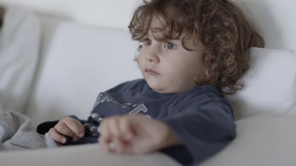 Słodki Chłopiec Kręconymi Włosami Leżący Kanapie Nowoczesnym Salonie Oglądający Telewizję — Wideo stockowe