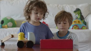 Çocuklar oyuncakları keşfediyor ve öğreniyor, birlikte oyun oynuyorlar, dijital tablet kullanıyorlar..