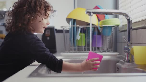 Genç Bir Çocuk Modern Bir Mutfakta Lavaboda Suyla Oynarken Eğleniyor — Stok video