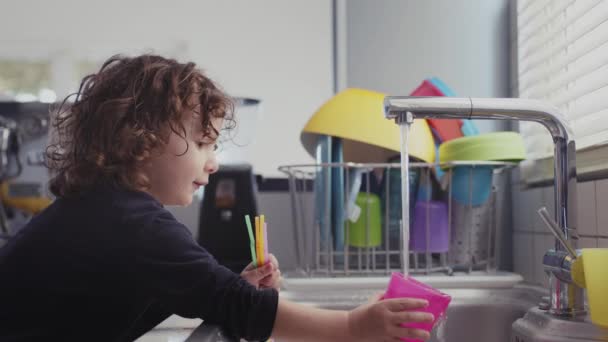 Маленький Ребенок Веселится Играя Водой Раковине Современной Кухне Наполняет Пластиковый — стоковое видео