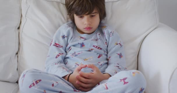 Młody Chłopiec Przytulnej Piżamie Nadrukiem Samolocie Siedzi Kontemplacyjnym Wyrazem Twarzy — Wideo stockowe