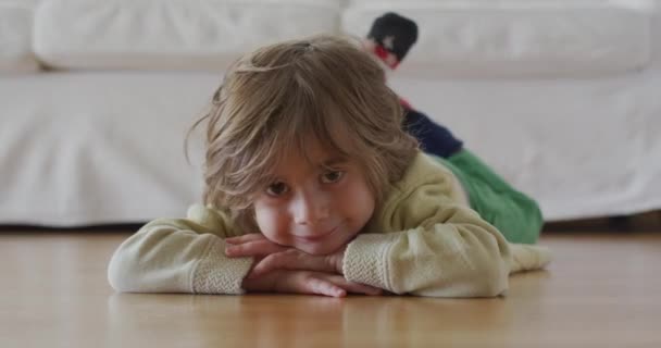 Zadowolone Dziecko Leży Drewnianej Podłodze Wewnątrz Domu Spoczywając Przedramionach Jasnymi — Wideo stockowe