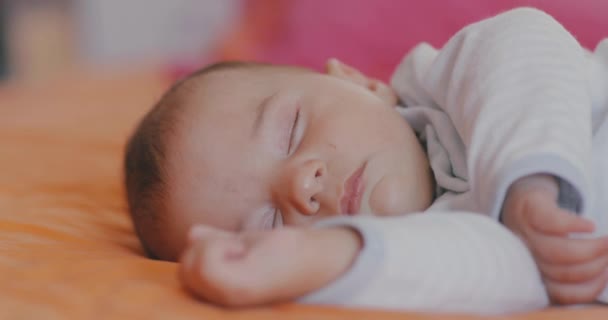 Spokojne Noworodek Śpi Miłą Ekspresją Owinięte Biel Leżące Pomarańczowym Kocu — Wideo stockowe