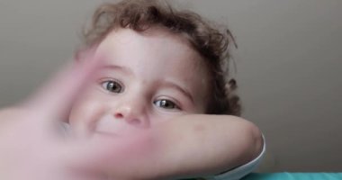 Dalgalı saçlarıyla turuncu oyun parkının kenarına bakan meraklı bir çocuk. Gözlerinde bir beklenti ve neşe karışımı..