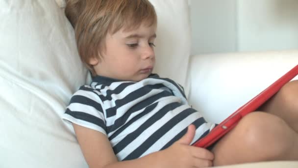 Dreng Med Blond Hår Fokuserer Intenst Digital Tablet Liggende Tilbage – Stock-video
