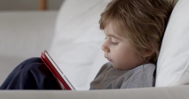 Egy Szőke Hajú Fiú Erősen Koncentrál Egy Digitális Tabletre Egy — Stock videók