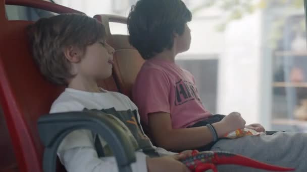 一个带着耳机的沉思的小男孩坐在一辆开动的公共汽车的窗前 带着沉思的神情凝视着外面 — 图库视频影像