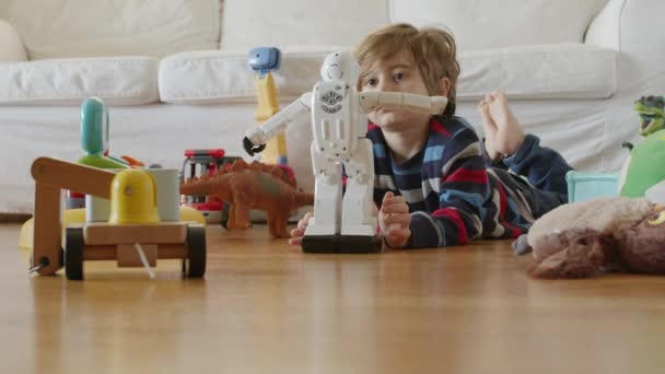 Młody Chłopiec Blond Włosami Skupia Się Zabawie Białym Robotem Wśród — Wideo stockowe