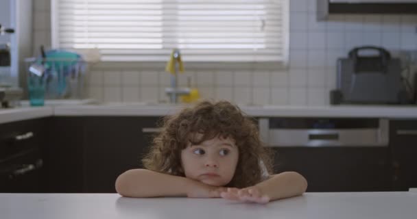 Kudrnatý Chlapec Opřel Bradu Ruce Kuchyňského Pultu Oči Vytřeštěné Zamyšleným — Stock video