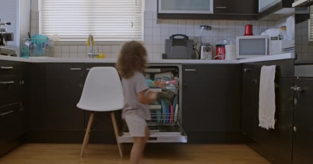 Boy Stands Stool Reach Open Dishwasher Carefully Placing Dishes Showing — Stock Video