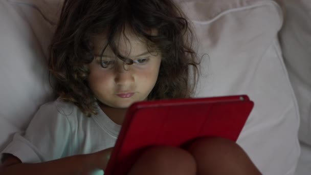 Kıvırcık Saçlı Küçük Bir Çocuk Dijital Tablete Odaklanıyor Kanepeye Uzanıyor — Stok video