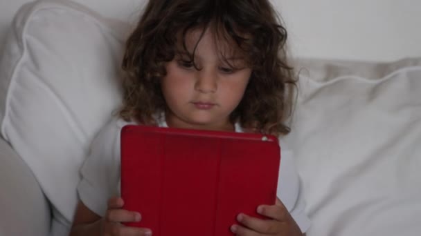 Malé Dítě Dlouhými Kudrnatými Vlasy Zaměřeno Červenou Digitální Tabletu Pohodlně — Stock video