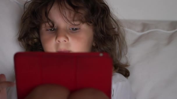 Kıvırcık Saçlı Küçük Bir Çocuk Dijital Tablete Odaklanıyor Kanepeye Uzanıyor — Stok video