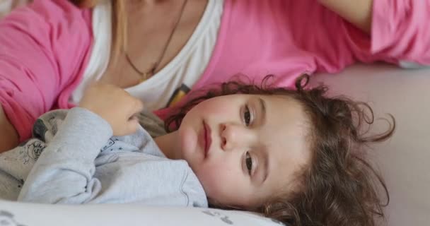 一个孩子躺在床上 而一个关心的母亲则轻轻地用额头温度计检查发烧情况 这表明她正在接受家庭医疗护理 — 图库视频影像