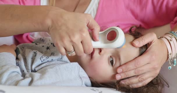 아이는 걱정되는 어머니가 부드럽게 확인하기 온도계를 사용하는 의료의 순간을 나타내는 — 비디오